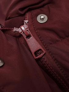 Detail of burgundy quilted jacket featuring high-quality metal zipper and snap buttons