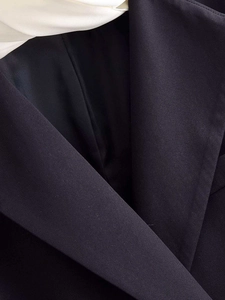 Macro detail of dark blue blazer collar with white contrast lapel and premium texture