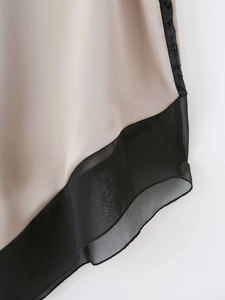 Detail of champagne satin fabric with black lace stitching and chiffon hem on dress