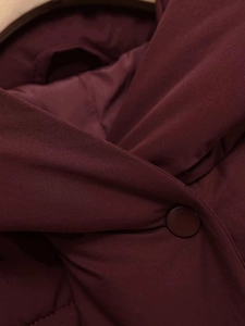 Detail of wine red padded jacket showing matte fabric texture and tonal round button