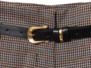 Detail of houndstooth wide-leg trousers with a black leather belt and gold buckle