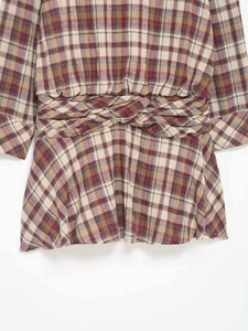 Dettaglio dell'abito mini a quadri con nodo intrecciato in vita e classico motivo tartan