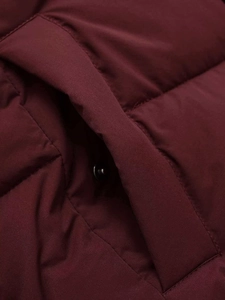 Macro shot of the side pocket with a black metal snap button on a burgundy quilted coat