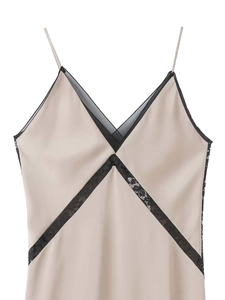 Close-up of elegant champagne satin dress with delicate black lace trim at V-neckline
