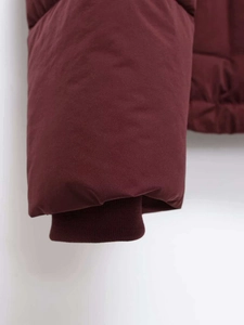 Close-up of windproof ribbed cuffs on a burgundy winter hooded jacket with matte fabric