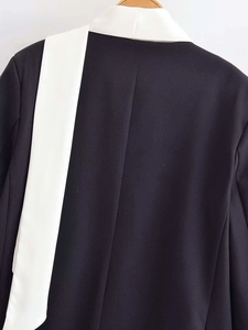 Close-up of black oversized blazer with contrast white lapel and textured fabric