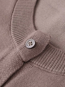 Détail macro du col en tricot côtelé et bouton sur la robe en maille marron