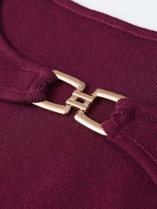 Détail de la boucle en métal doré sur la robe en maille bordeaux à texture côtelée