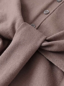 Détail d'une robe en maille marron avec texture, boutons et ceinture nouée à la taille