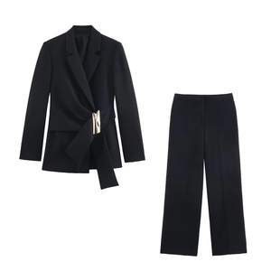 Detail of black blazer suit featuring asymmetric buckle closure and high waist straight pants