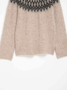 Detailed macro of the Nordic geometric jacquard pattern on a beige knit sweater