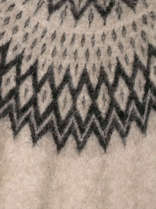 Macro view of beige jacquard knit sweater with soft mohair texture and geometric patterns