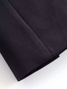 Detailed close-up of premium black fabric stitching and fine texture on blazer sleeve