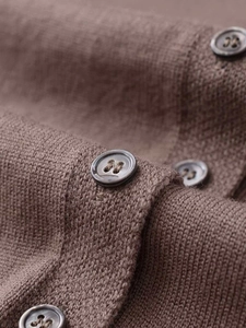 Détail du bouton en résine ronde et texture de maille fine sur un cardigan marron