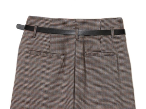 Detail of retro brown houndstooth trousers featuring high waist and slim black belt
