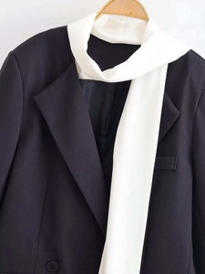 Detail of classic black double-breasted blazer with white satin scarf decoration