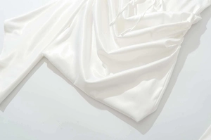 Dettaglio dell'abito in raso bianco con eleganti increspature e trama in seta