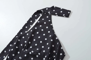 Detail of black halter mini dress featuring white polka dots and pleated chest design