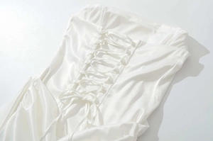 Détail d'une robe en satin blanc avec laçage croisé style corset à l'arrière du dos