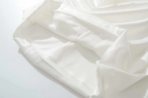 Gros plan sur l'ourlet de la robe en satin blanc avec tissu brillant et double couture