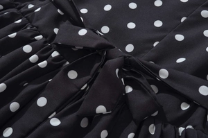 Detail of black and white polka dot halter dress featuring a delicate bow tie and soft fabric