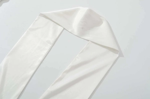 Dettaglio della trama in raso bianco liscio su un abito estivo senza spalline elegante