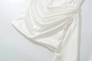 Gros plan du tissu satiné blanc élégant montrant la texture froncée de la robe