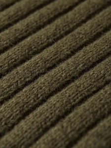 Macro di tessuto a maglia a coste verde oliva che mostra consistenza spessa e fibre