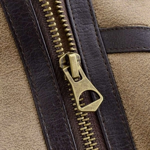 Macro shot of vintage brass zipper on khaki faux suede jacket with precision stitching