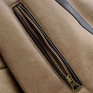 Detail of vintage brass zipper on khaki suede jacket with high-quality leather piping
