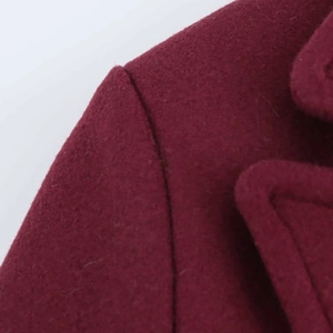 Close-up of wine red wool coat showing precise shoulder stitching and thick fabric texture