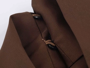 Close-up of dark brown twill fabric featuring two black buttons and reinforced stitching