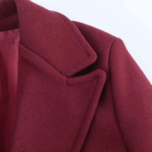 Close-up detail of burgundy wool coat notched lapel showing fine fabric texture and stitching