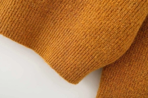 Close-up of mustard yellow thick knit sweater featuring chunky ribbed texture detail