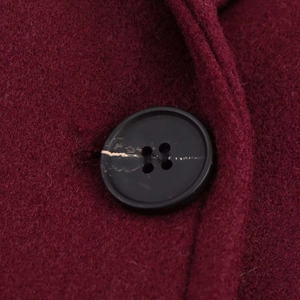 Macro detail of wine red wool coat fabric texture and a black four-hole button