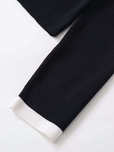 Detailed macro view of black knit sweater cuff with white ribbed texture and contrast trim