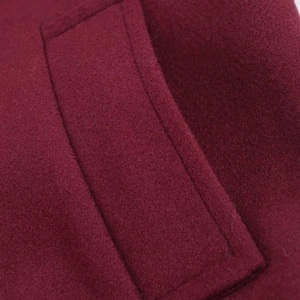 Close-up of burgundy wool coat showing elegant pocket flap and premium stitching texture