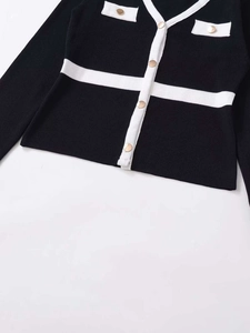 Detail of knit cardigan showing gold buttons and white contrast trim on pockets
