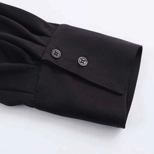 Détail de la manchette noire à manches longues avec double boutonnage et plis délicats