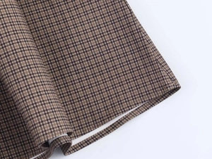 Close-up of the vintage tan plaid fabric and high-quality hem stitching on the dress