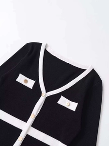 Detail of knit cardigan showing gold metal buttons and black-white contrast trim