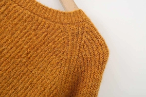 Close-up of mustard yellow chunky knit sweater showing rib knit collar and fuzzy texture