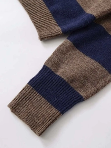 Detailed close-up of brown and navy striped knit sweater with ribbed cuffs and soft texture