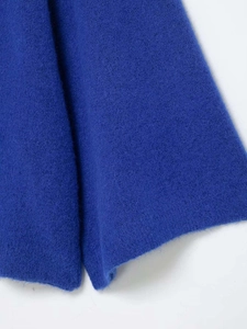 Macro shot of cobalt blue knit fabric showing soft texture and premium wool blend fibers