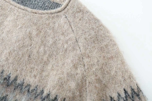 Close-up of beige crewneck jacquard knit sweater with soft mohair texture and grey patterns