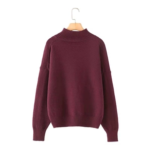 Detail of burgundy turtleneck knit sweater featuring ribbed cuffs and wood hanger display