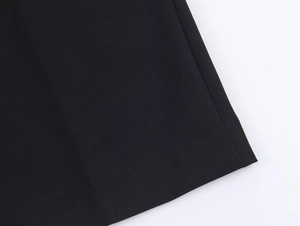 Close-up of black blazer fabric texture and precision hem stitching on the suit