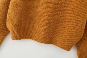 Detail of chunky knit fabric in ginger orange showing ribbed texture and soft fibers