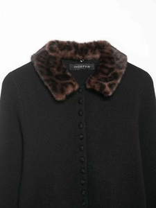 Détail d'un cardigan noir en maille avec col en fausse fourrure léopard et boutons en tissu