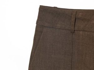 Close-up of waist detail and belt loops on khaki wool blend trousers with twill texture